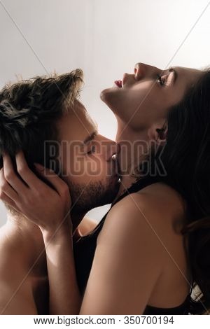 Side View Of Boyfriend Kissing Attractive Girlfriend With Closed Eyes