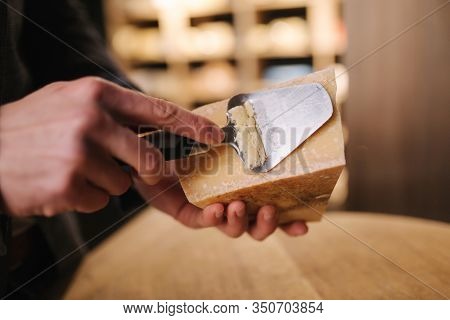 Young Worker Slicing Cheese In Shop. Tasty Cheese