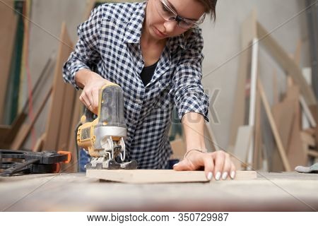 Woman carpenter working with fretsaw