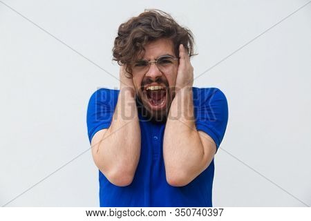 Front View Of Angry Young Man Screaming. Angry Man Screaming Loud With Wide Open Mouth And Holding H