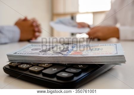 Photos Of Dollars And Bank Notes On The Calculator At The Table.