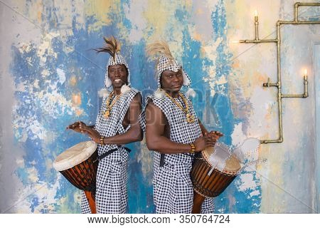 A Group Of People In Traditional African Costumes Playing Jembe Drums