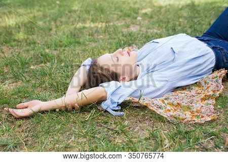 Relaxed Young Woman Lying On Headkerchief On Ground In Park. Beautiful Lady Relaxing Outdoors. Leisu
