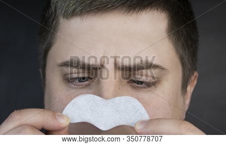 A Man Puts On And Removes A Strip For The Nose From Black Dots. Coal Cleaning Strips From Blackheads