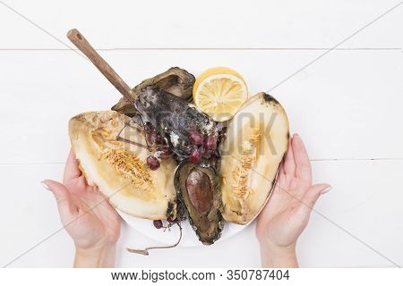 Woman Holds A Plate With Rotten Fruits, In Which A Knife Is Stuck, Stop Wasting Food Concept, Eating