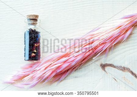 Small Old Vintage Glass Bottle With Cork With Floral Tea And Blue And Pink Petals On Wooden Backgrou
