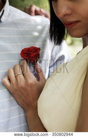 Brunette Bride Puts Groom On Boutonniere - One Red Rose On Wedding Day. Hands Of New Wife On Husband