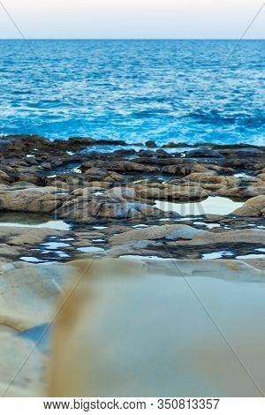 Vertical Close-up Picture Of Stone Coastline With Blue Sea And Sky In Evening. Maltese Coast In Slie
