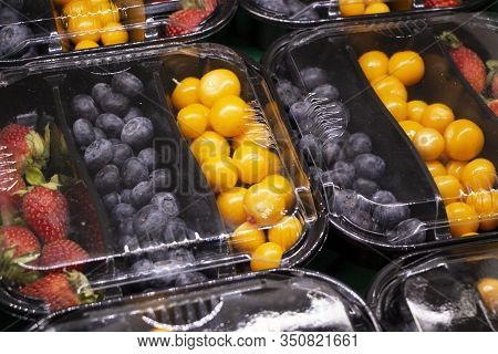Fresh Berries Are Packed In Trays. Vitamin-rich Fruits Are Packaged In Boxes. A Variety Of Fruits Fo
