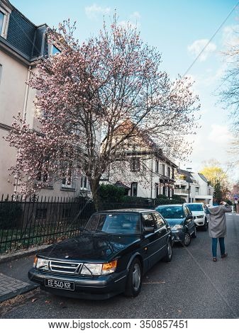 Strasbourg, France - Mar 10, 2019: Woman Walking Near Beautiful Vintage Saab Black Cloro Sedan Car A