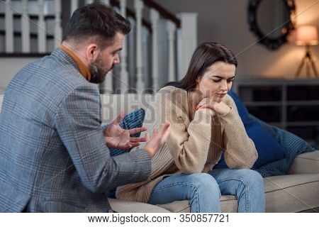 Angry Couple Having Argument Or Breakup. Young Husband And Wife Having Quarrel While Sitting On A Co