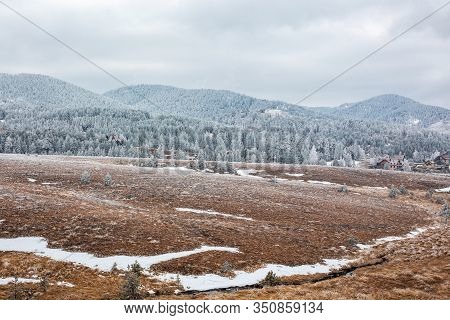 Snowy Mountain Glade With Houses In The Distance