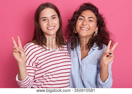 Indoor Shot Of Two Cheerful Women Friends Posing Isolated Over Pink Background In Studio, Attractive