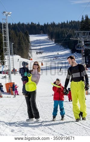 Parents With Children Walking On Snow In Ski Resort. Family Winter Vacation