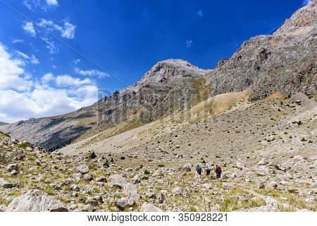 Turkey, Chamard - August 3, 2019: Tourists Walk Along The Road Through The Mountain Landscape In The