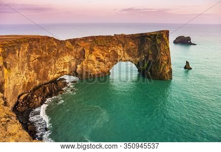Natural Lava Arch In The Sea. Cape Dyrholaey, Coast Of Iceland. Popular Tourist Attraction. Beauty W