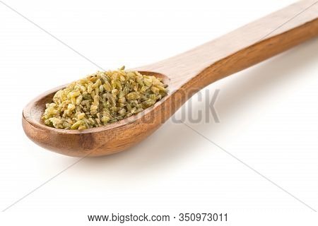 Heap Of Uncooked, Raw Freekeh Or Firik, Roasted Wheat Grain, In Wooden Spoon Over White Background W