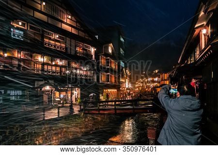 Tourists Are Traveling The Famous Ginzan Onsen While Snow Is Falling Down.