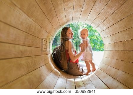 Mother And Baby Playing On The Playground In The Wooden Tunnel. Eco-friendly Natural Playground.