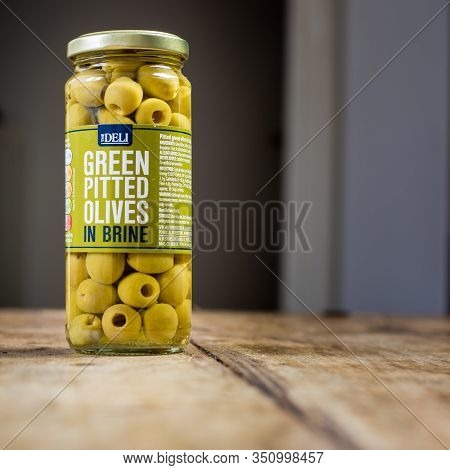Perth, Scotland - 11 November 2019: Green Pitted Olives In Brine Isolated On Vintage Wooden Table