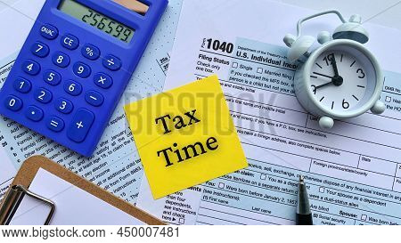 Top View Of Text On Yellow Notepad - Tax Time. With Tax Form, Calculator, Alarm Clock And Pen Backgr