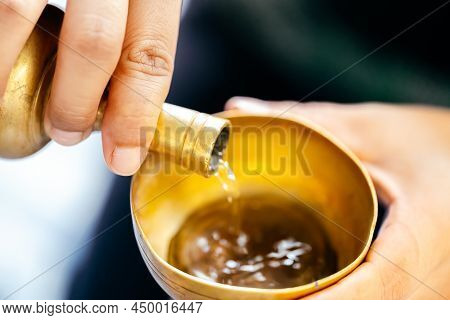 Hand Person Is Pouring Water With Brass Cup. Concept Of Making Merit And Dedicating Charity In Buddh