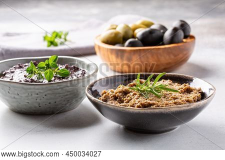 Tapenade - Paste Made From Olives. Bowls With Spreadable Black And Green Olive Cream On Concrete Bac