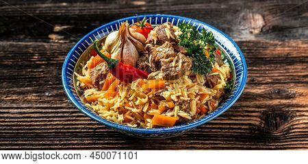 Traditional Uzbek Meal Called Pilaf. Rice With Meat On Plate With Oriental Ornament On A Dark Wooden