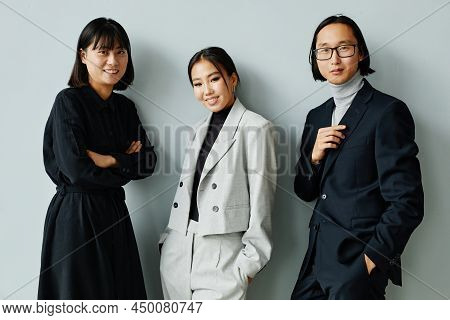 Waist Up Portrait Of Modern Asian Business Team Smiling At Camera Standing Against Miniman Backgroun