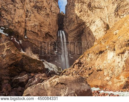 A High Mountain Waterfall Flows Down In The Rocks Of A Suburban Gorge In The North Caucasus On An Au