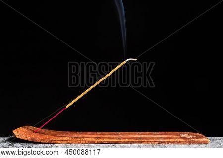 Side View Of Incense Stick Stands On A Wooden Stand Isolated On A Black Background.