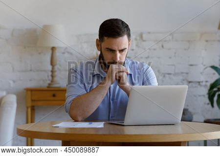 Serious Man Read E-mail On Laptop Looks Concerned Or Puzzled