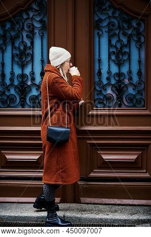 Woman In Coat And Eyglasses With Coffee Cup Smiling And Entry At Door. Happy Emotion Portrait