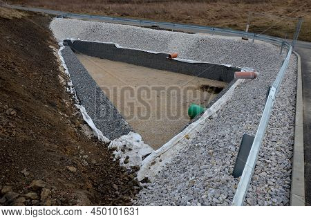 Triangle-shaped Drainage Pond With Stone Wall Paneling And Gabion Walls. The Water Slows Down During