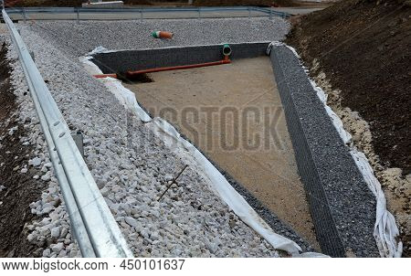 Triangle-shaped Drainage Pond With Stone Wall Paneling And Gabion Walls. The Water Slows Down During