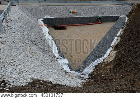 Triangle-shaped Drainage Pond With Stone Wall Paneling And Gabion Walls. The Water Slows Down During