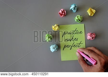 Top View Image Of Hand Holding Pen, Crumpled Paper And Green Paper With Text Practice Makes Perfect.