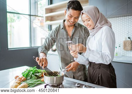 Muslim Couple Cooking Together In The Kitchen While Look At Video