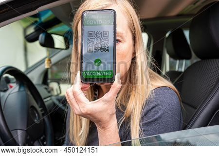 Driver In Car Shows A Digital Covid-19 Immunity Vaccine Passport, New Normal Travel Concept