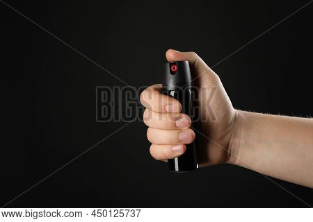 Man Holding Pepper Spray On Black Background, Closeup. Space For Text