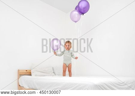 Cute Funny Caucasian Blonde Baby Girl,toddler Of 1,2 Year Old Playing On Bed With Big Purlple Balloo
