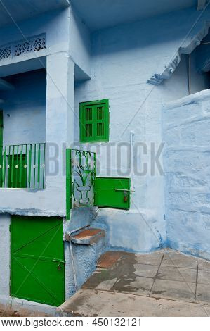 Traditional Blue Coloured House, Green Door And Window Of Jodhpur City, Rajsthan, India. Blue Is Sym