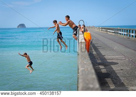 Tolaga Bay New Zealand - February 5 2022; Local Boys Jumping Of Tolaga Bay Wharf Under Encouragement