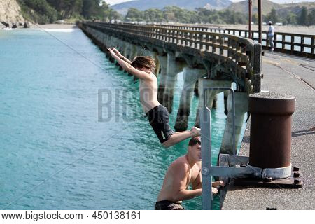 Tolaga Bay New Zealand - February 5 2022; Local Boys Jumping Of Tolaga Bay Wharf Under Encouragement