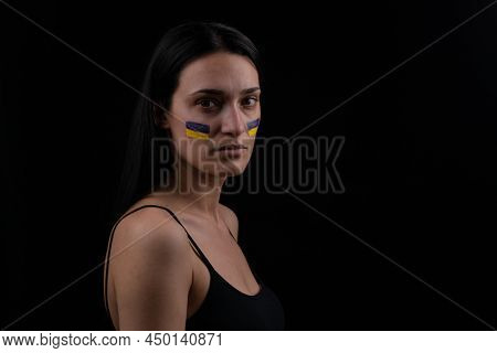 Portrait Of Serious Ukrainian Woman With Blue And Yellow Ukrainian Flag On Her Cheek. The Symbol Of 