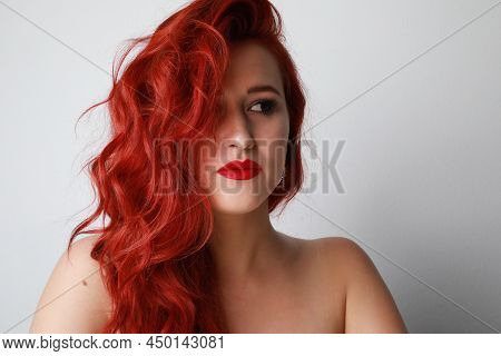 Stunning Young Woman With Long Red Hair Looks Aside Posing On White Background.