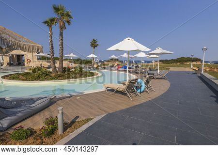 View Of Territorium Of Modern Resort In Greece. Outdoor Pool And Restaurant On Blue Sky Background. 