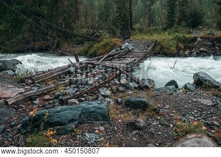 Atmospheric Rainy Landscape With Forest And Bridge Over Mountain River. Dark Forest Scenery With Pow