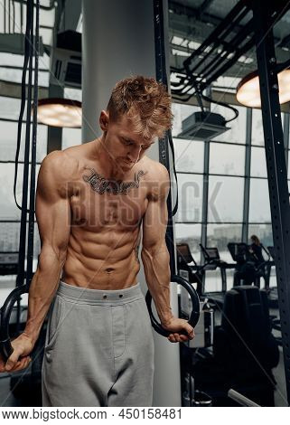 Strong Man Doing Exercise On To Gymnastic Rings At Gym. Fit Male Athlete Training On Gymnastic Rings