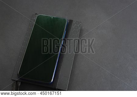 Notepad And Mobile Phone On A Black Background, Table. Financial Calculations, Black Shades